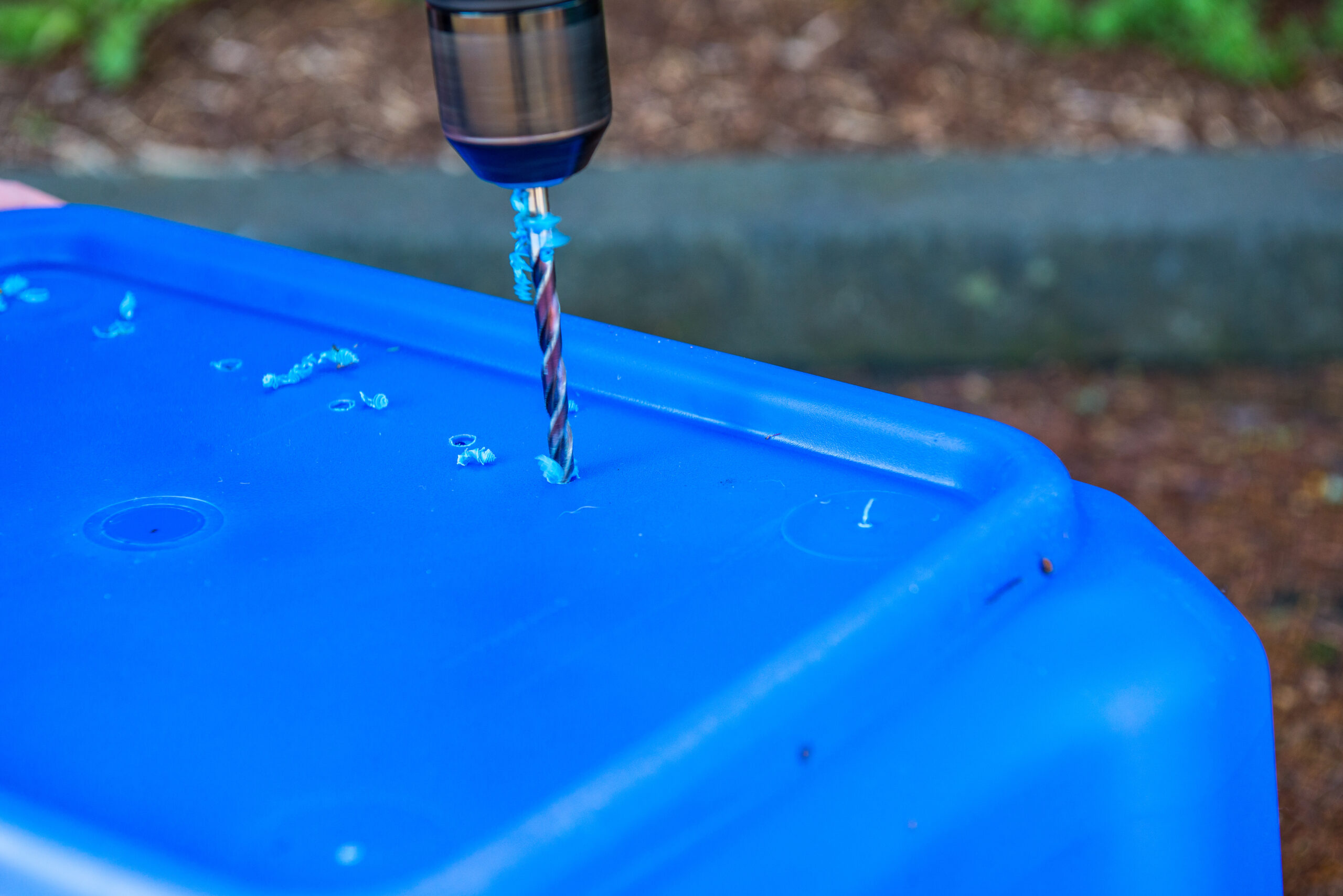 Blue plastic bin with holes being drilled into it